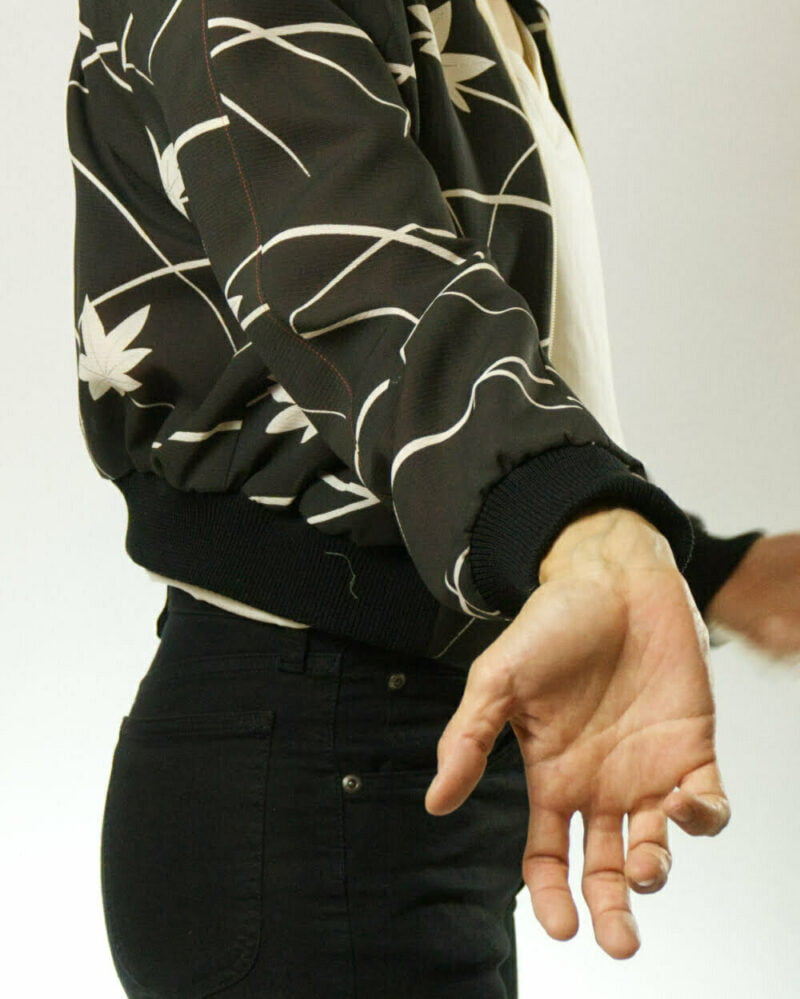 Nahansicht von schwarzer Bomberjacke aus Kimono mit weissen Ahornblättern und weissen Linien, Fokus auf schwarzem Ärmelbündchen