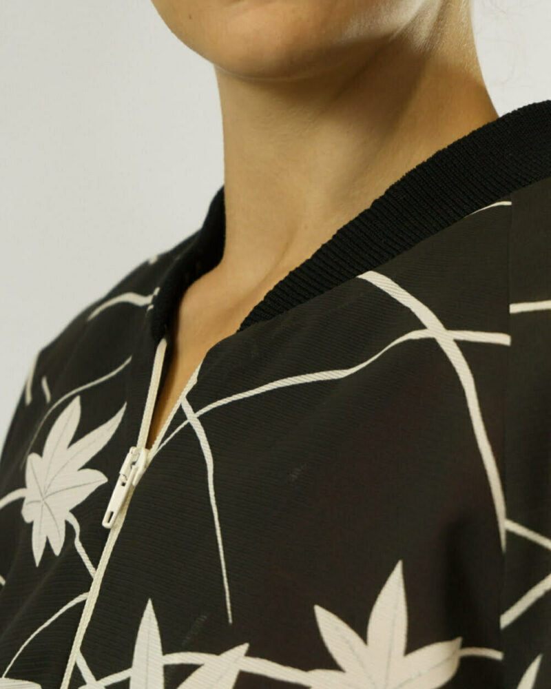 Nahansicht von schwarzer Bomberjacke aus Kimono mit weissen Ahornblättern und weissen Linien, Fokus auf schwarzen Kragen und weissem Reissverschluss