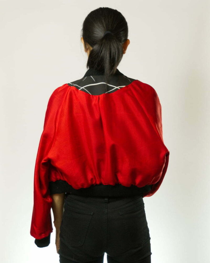 Hinteransicht von Frau schwarzer Bomberjacke aus Kimono mit weissen Ahornblättern und weissen Linien, links herum getragen mit Sicht auf rotem Innenfutter