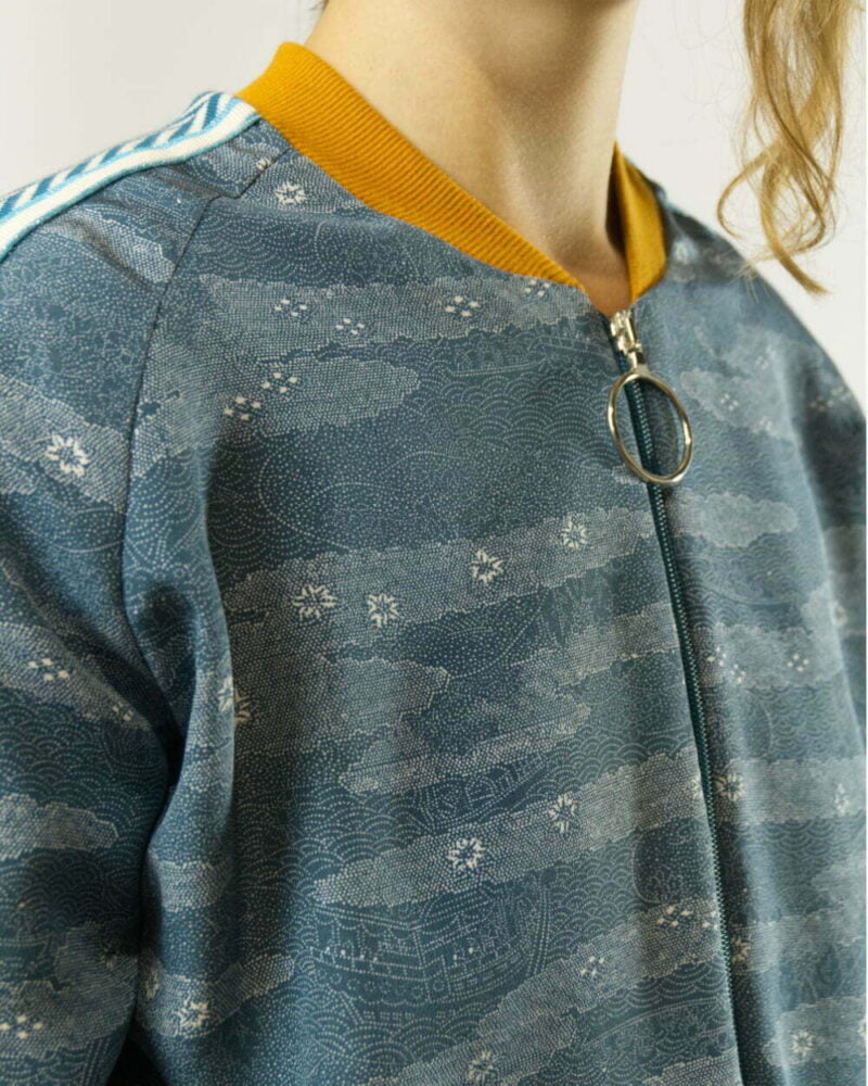 Nahansicht von blauer Bomberjacke aus Kimono. Fokus auf ockergelbem Kragen und Reissverschluss