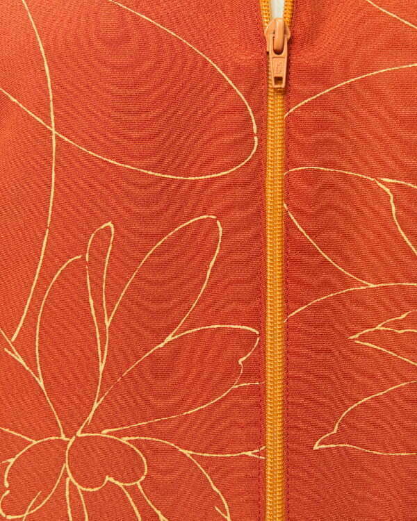 Nahansicht von ziegelroter Bomberjacke aus Kimono mit Fokus auf gelben Chrysanthemen in Linienform und gelbem Reissverschluss