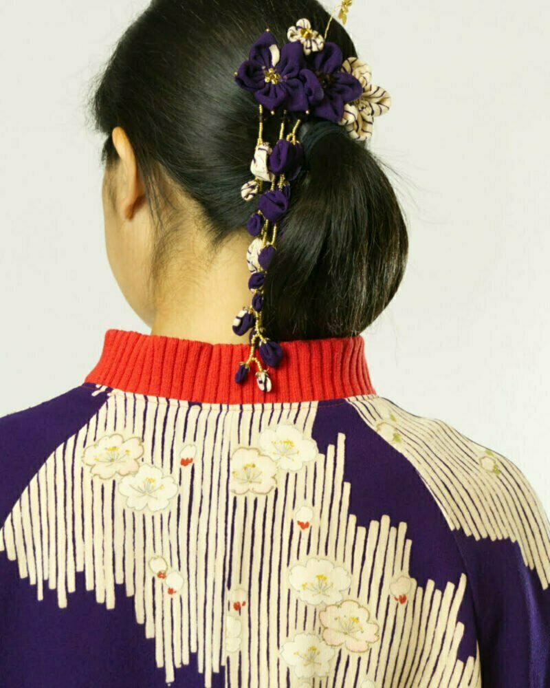 Hinteransicht von Frau mit lila Bomberjacke aus Kimono mit weissen Streifenmustern, weissen und rosa Kirschblüten mit goldenen Akzenten. Fokus auf roten Kragen aus rotem, grobgeripptem Baumwollrundstrick