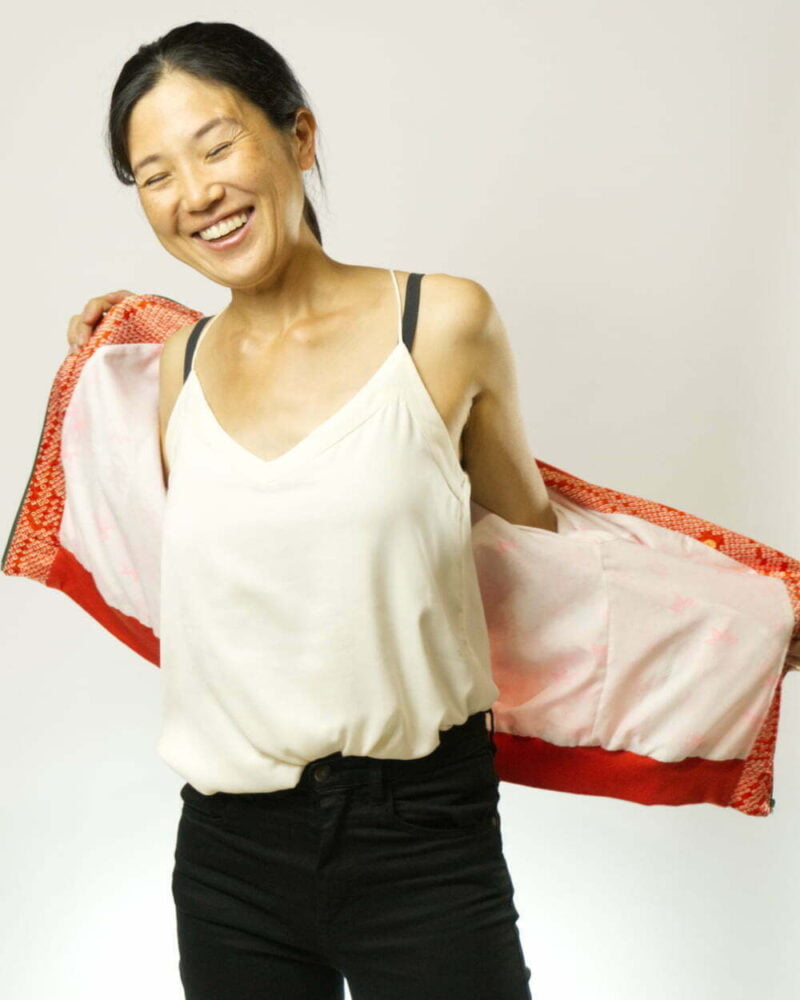 Vorderansicht von Frau mit offen getragener Bomberjacke aus Faux Shibori Kimono. Fokus auf weissem Innenfutter mit pinken Ahornblättern